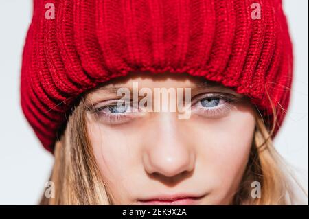 Contemplare la ragazza in maglia cappello contro muro Foto Stock