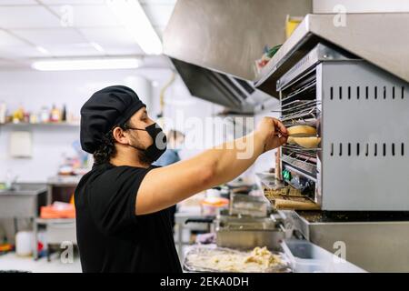 Chef maschile preparare il pane in forno in cucina ristorante durante COVID-19 Foto Stock