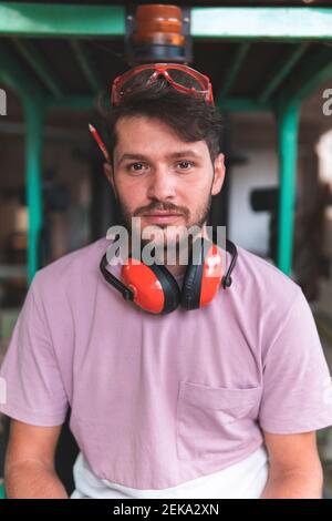 Bel falegname maschio con indumenti da lavoro protettivi in officina Foto Stock