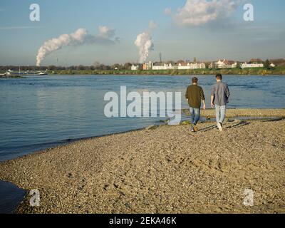 Padre e figlio che camminano contro il cielo sulla riva del fiume Foto Stock