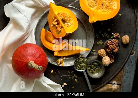 Noci, semi di zucca e squash di kuri rossi su una teglia rustica Foto Stock