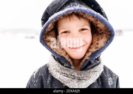 Primo piano ritratto di un ragazzo sorridente che indossa abiti caldi Foto Stock