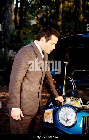 Uomo d'affari che esamina un'automobile rotta Foto Stock