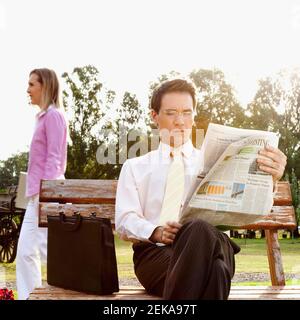 Imprenditore leggendo un giornale in un parco Foto Stock