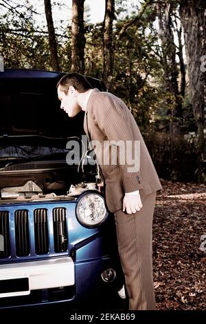 Uomo d'affari che esamina un'automobile rotta Foto Stock