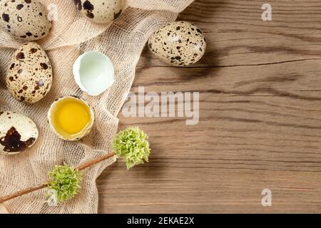 Composizione di diverse uova di quaglia su tessuto decorativo su un tavolo di legno, spazio di copia, flatlay. Foto Stock
