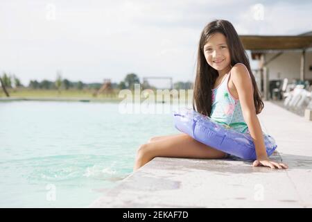 Ritratto di una ragazza seduta al bordo della piscina Foto Stock