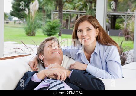 Uomo d'affari che ascolta la musica con una donna d'affari accanto a lui Foto Stock