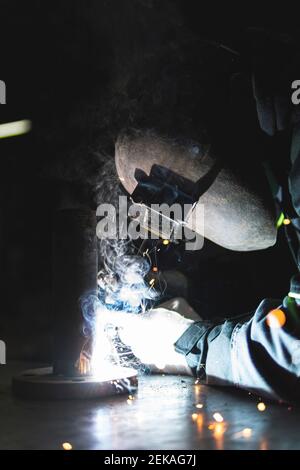 Saldatore professionale maschile in elmetto di saldatura in officina Foto Stock