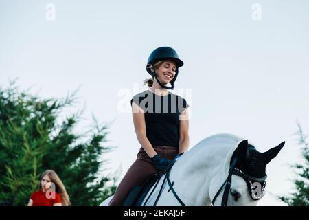 Donna sorridente che guarda il cavallo durante il weekend Foto Stock