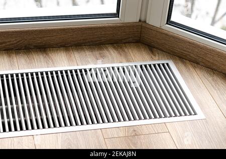 Griglia di protezione integrata nel pavimento per il riscaldamento dei vetri panoramici. Griglia di riscaldamento con ventilazione a pavimento in parquet Foto Stock