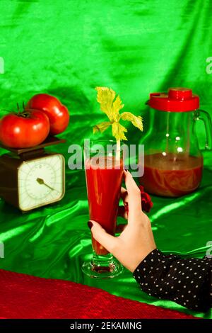 Donna che tiene un bicchiere di succo di pomodoro con foglia di sedano Foto Stock
