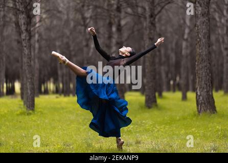 Giovane ballerina con balli alzati a mano mentre si sta in piedi foresta Foto Stock