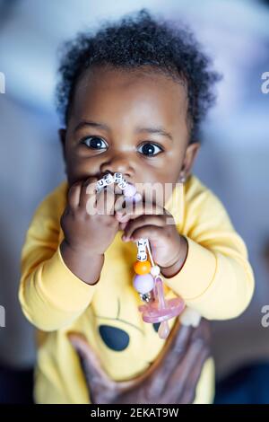 Baby girl masticare giocattolo mentre tenuto da uomo Foto Stock