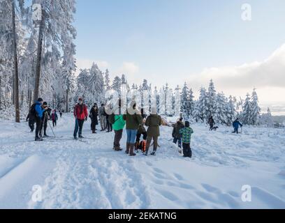 Repubblica Ceca, Brdy Mountains, 9 gennaio 2021: Gruppo di persone e sci di fondo su una passeggiata su strada innevata in foresta invernale con neve coperta Foto Stock