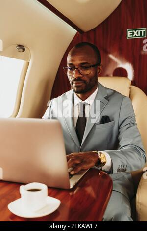 Giovane imprenditore maschile che lavora su un computer portatile mentre viaggia in privato getto Foto Stock