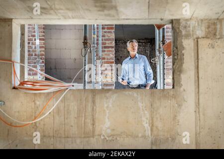 Architetto attento con tablet digitale mentre si trova in cantiere Foto Stock