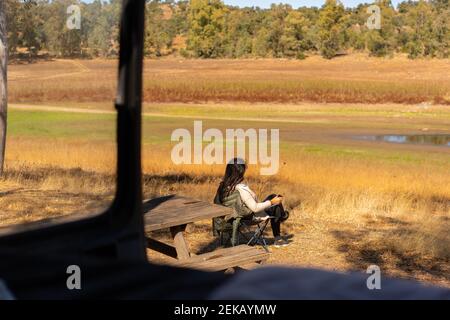 Donna caucasica che beve caffè seduto su una sedia su un punto selvaggio vita vita visto da dentro camper, in Spagna Foto Stock