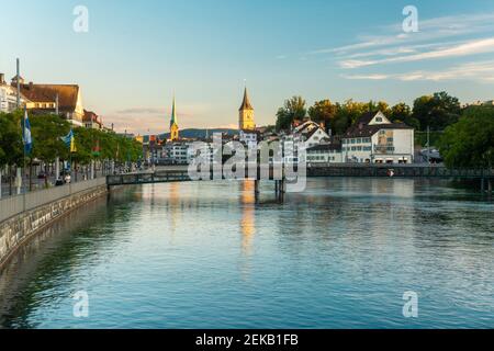 Lungofiume del fiume Limmat con la chiesa di San Pietro e Fraumunster a Zurigo, Svizzera Foto Stock