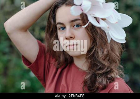 Ragazza con occhi blu che indossa magnolia fiore in capelli Foto Stock