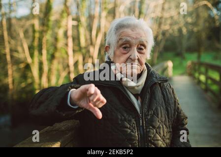 Donna anziana dispiaciuta che mostra i pollici verso il basso gesto durante l'inverno Foto Stock