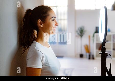 Giovane donna sorridente guardando attraverso stroboscope circolare in piedi casa Foto Stock