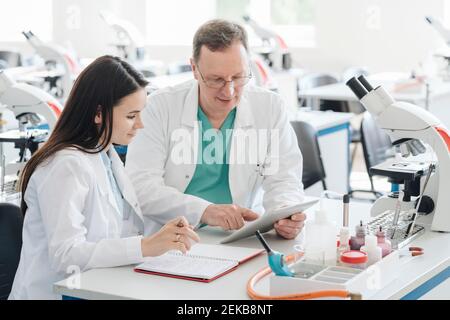 Scienziati in camici bianchi che usano compresse in laboratorio Foto Stock