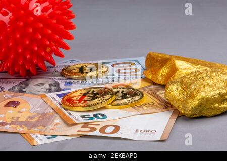 Crypto Currency, denaro sui mercati azionari globali vs Covid-19 concetto economico: Un coronavirus rosso accanto a monete di bitone e pezzi d'oro, EURO e DOLLARI USA Foto Stock