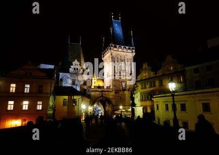 Torre del Ponte illuminata dal Ponte Carlo nella città di Praga di notte Foto Stock