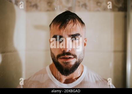 Uomo bagnato bearded con t-shirt che prende la doccia in bagno a. casa Foto Stock