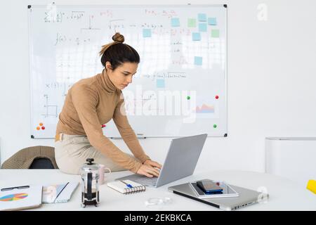 Giovane studentessa che usa il computer portatile mentre fa la matematica Foto Stock