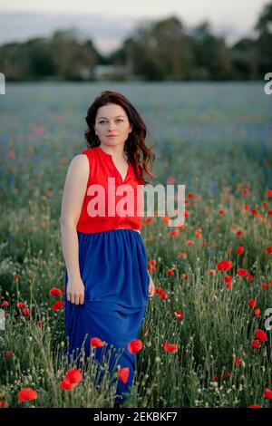 Bella donna tra fiori a piedi in campo papavero Foto Stock