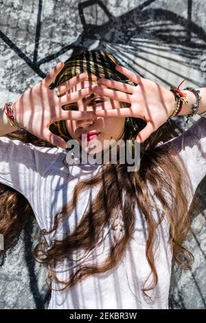 Giovane donna che nasconde il viso con le mani mentre si trova su pavimento in cemento Foto Stock