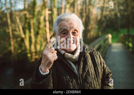 Donna anziana gesturing mentre si è in piedi sulla passerella durante l'inverno Foto Stock