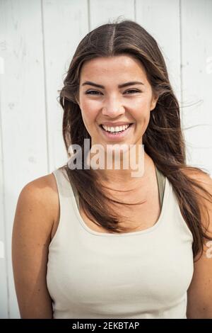 Felice giovane donna in tank top contro capanna spiaggia Foto Stock