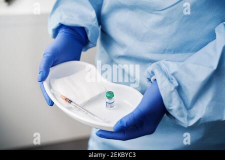 Medico femminile che tiene la vaccinazione COVID-19 in un vassoio medico Foto Stock