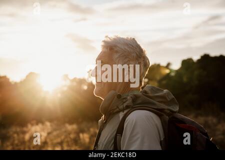 Uomo anziano in abiti caldi che guarda al tramonto Foto Stock