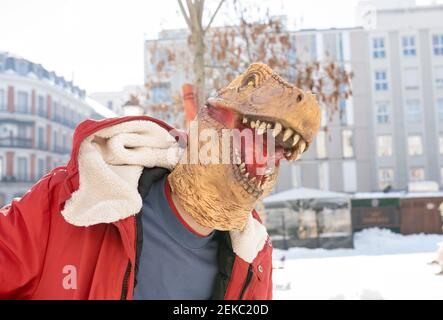 Uomo che indossa una maschera di dinosauro in piedi in città Foto Stock