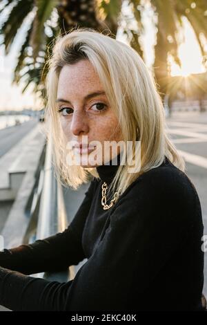 Giovane donna con capelli di media lunghezza appoggiati su ringhiera a. passeggiata Foto Stock