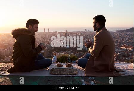 Coppia gay che ha fatto colazione sul punto di osservazione durante l'alba, Bunkers del Carmel, Barcellona, Spagna Foto Stock