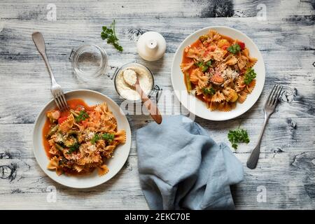 Due piatti di pasta con cravatta di prua con verdure e vegan Parmigiano Foto Stock