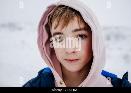 Ragazzo con occhi marroni in abiti caldi sulla neve Foto Stock