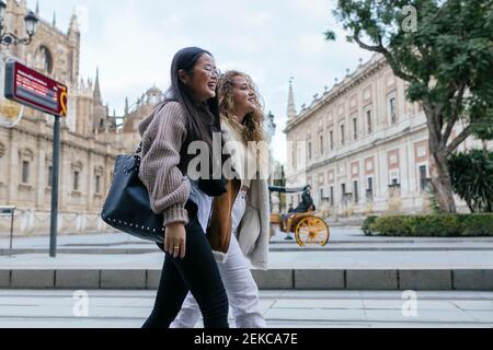 Amici multietnici che camminano sul marciapiede in città Foto Stock