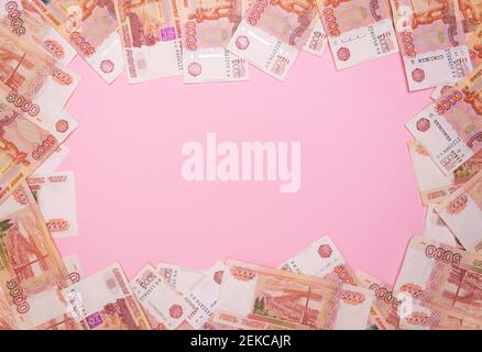 Banconote con un valore nominale di cinquemila rubli russi sotto forma di cornice su sfondo rosa. Vista dall'alto, spazio libero per il testo Foto Stock