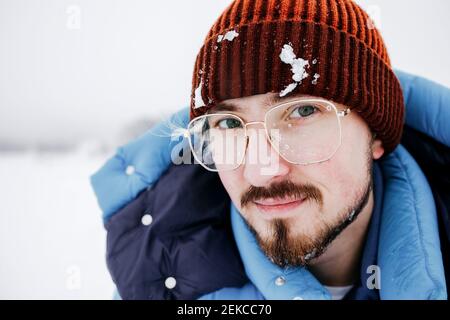 Giovane uomo con neve sul cappello a maglia durante le vacanze Foto Stock