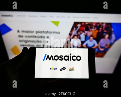 Persona titolare smartphone con logo della piattaforma brasiliana di e-commerce Mosaico tecnologia sullo schermo davanti al sito web. Mettere a fuoco il display del telefono. Foto Stock