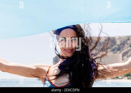 Ballerina sorridente che tiene il sarong blu nella giornata di sole Foto Stock