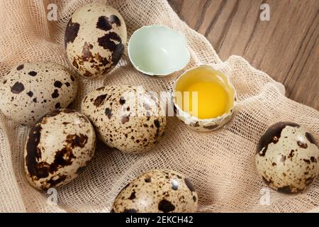 Composizione di diverse uova di quaglia su tessuto decorativo su un tavolo di legno primo piano, piatto Foto Stock