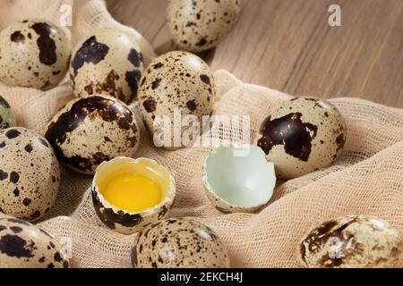 Composizione di diverse uova di quaglia su tessuto decorativo su un tavolo di legno da vicino, piatto. Foto Stock
