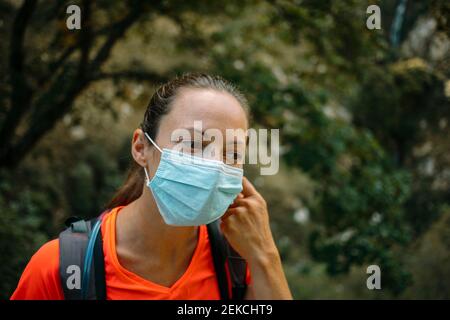 Donna che indossa una maschera protettiva che guarda via mentre si fa un'escursione al Cares Trail nel Parco Nazionale Picos De Europe, Asturias, Spagna Foto Stock